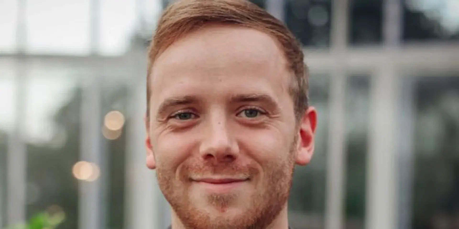 Close-up portret van een jongeman met kort lichtbruin haar en baard.