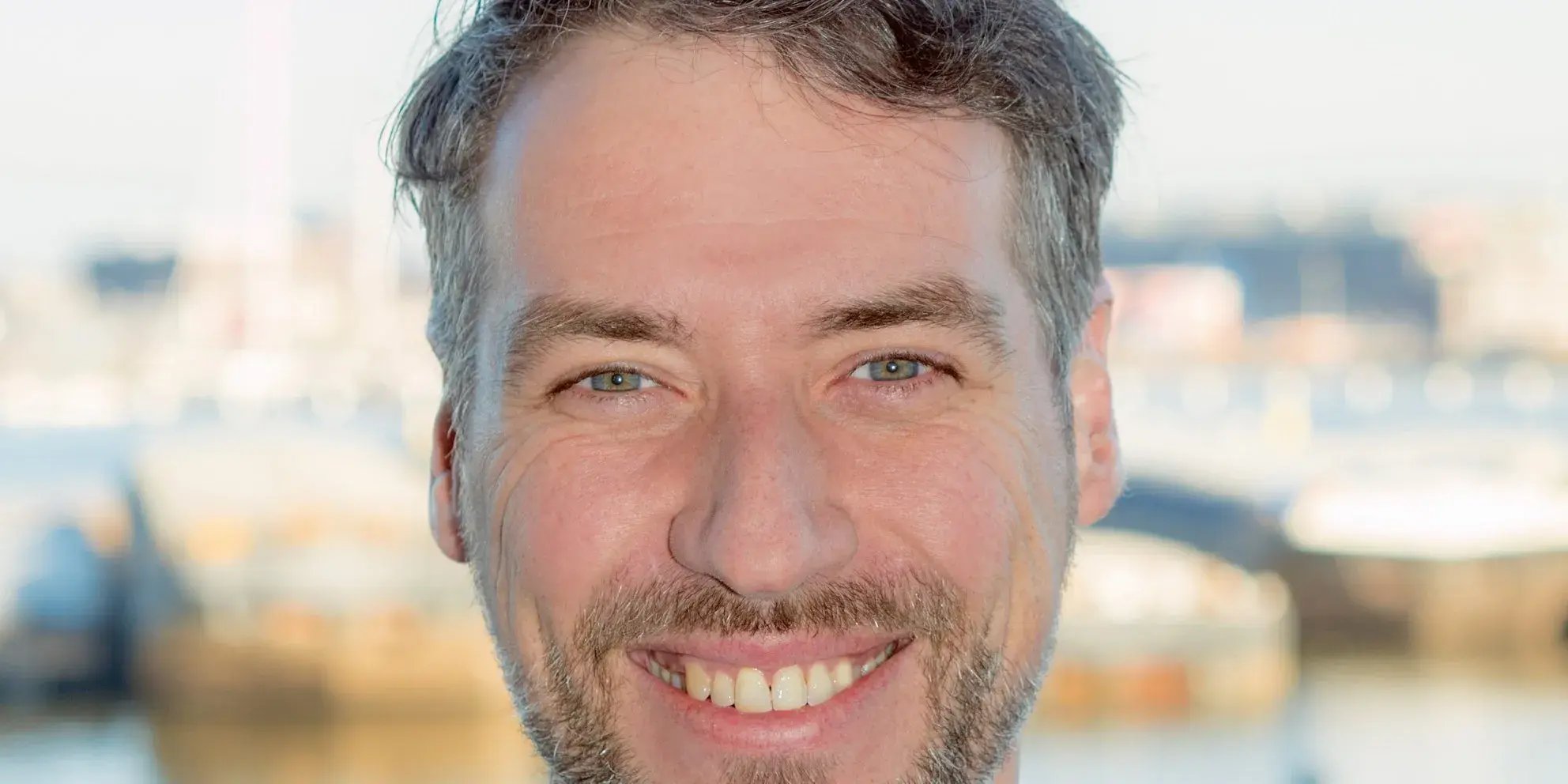 Portret van een man met baard die lacht.