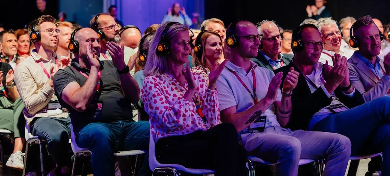 Mensen in publiek bij een presentatie met koptelefoons op