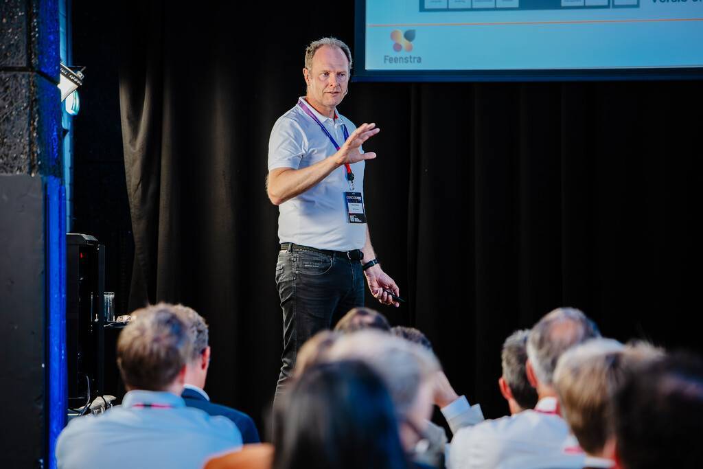 Presentator legt iets uit aan een publiek in een vergaderruimte.