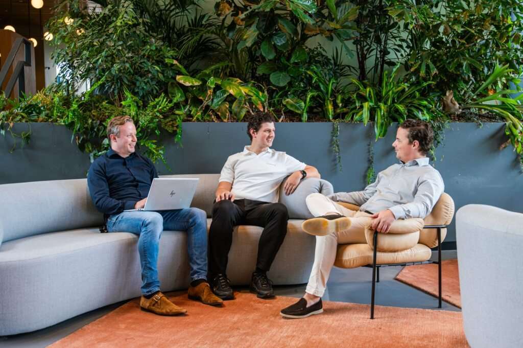 Drie collega's zitten op de bank en praten met elkaar.