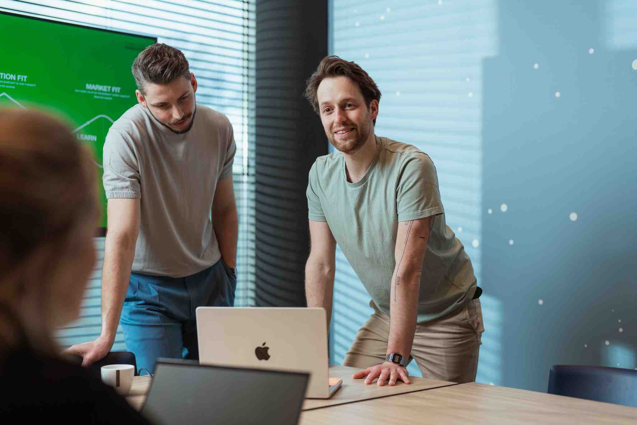Een man leunt op tafel en kijkt zijn collega aan.