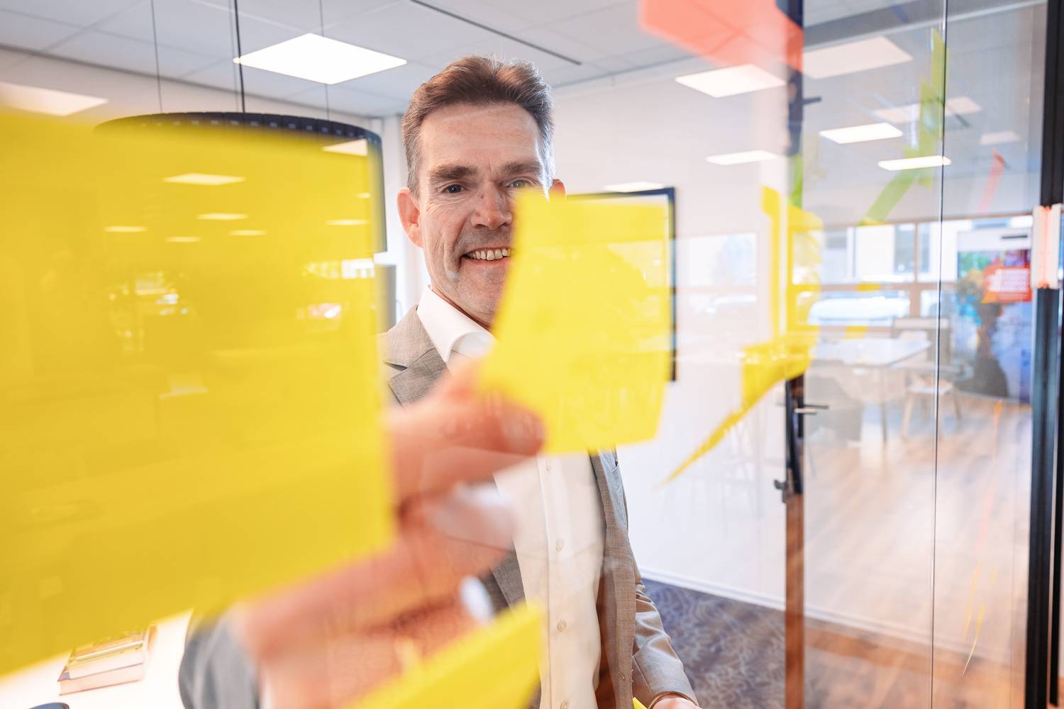 Een man plakt gele post-its op een glazen wand.