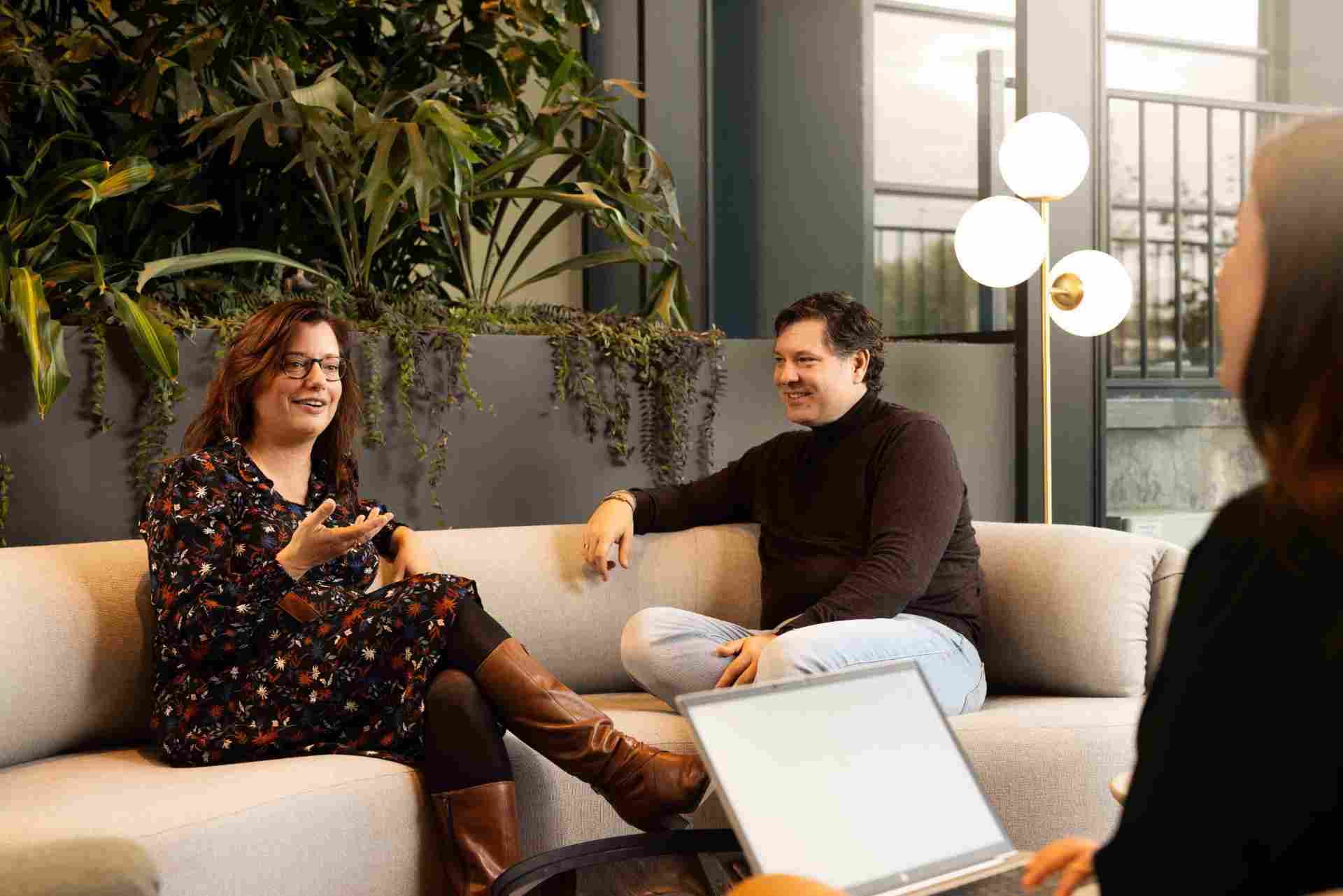 Drie collega's zitten op een bank en overleggen met elkaar.
