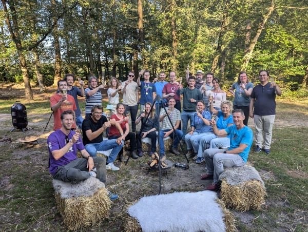 Grote groep collega's op bedrijfsuitje in het bos.