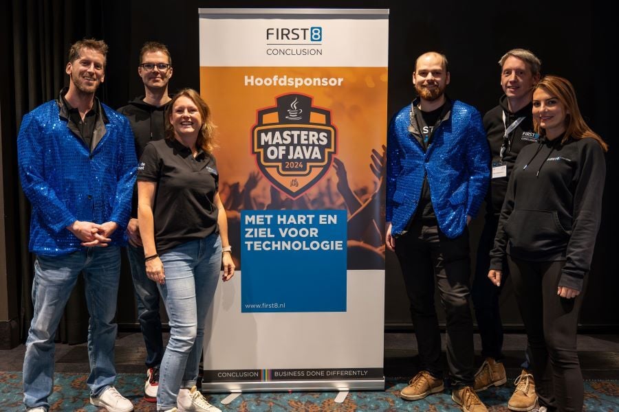 Een groep mensen staat naast een banner voor de Masters of Java 2024, met First8 als hoofdsponsor.