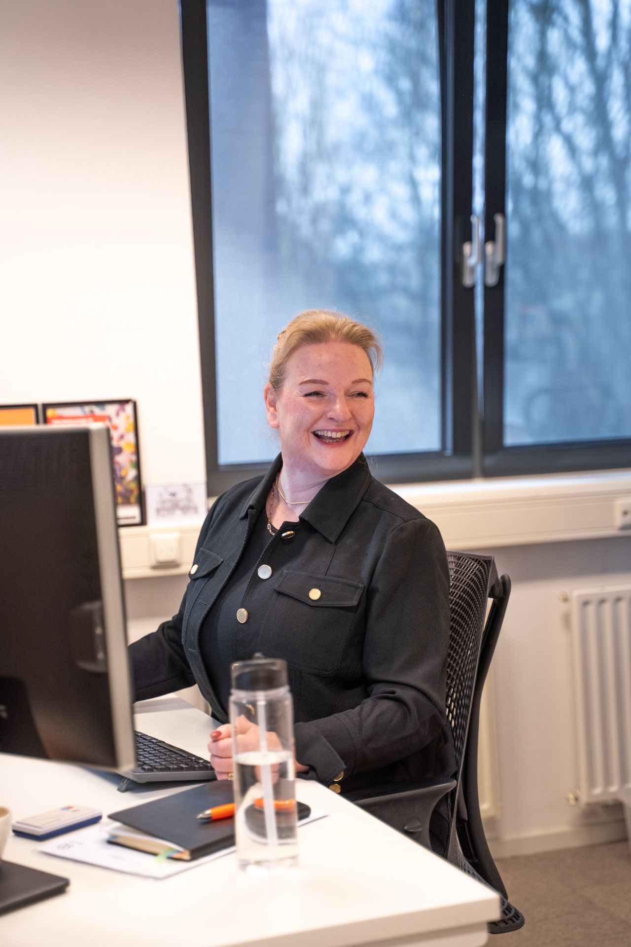 Vrouw met blond haar aan bureau.
