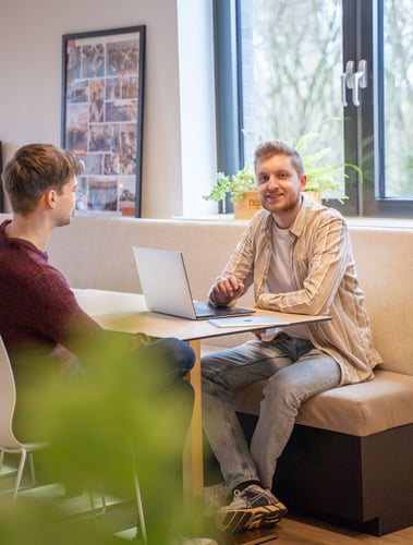 Twee mannen aan tafel met laptop.