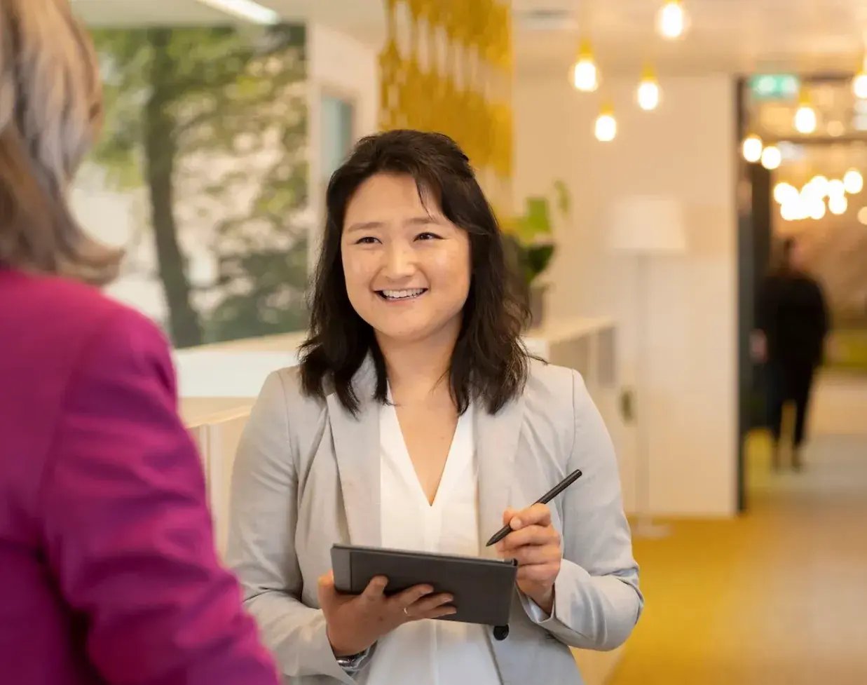 Aziatische vrouw met iPad in gesprek met vrouw.
