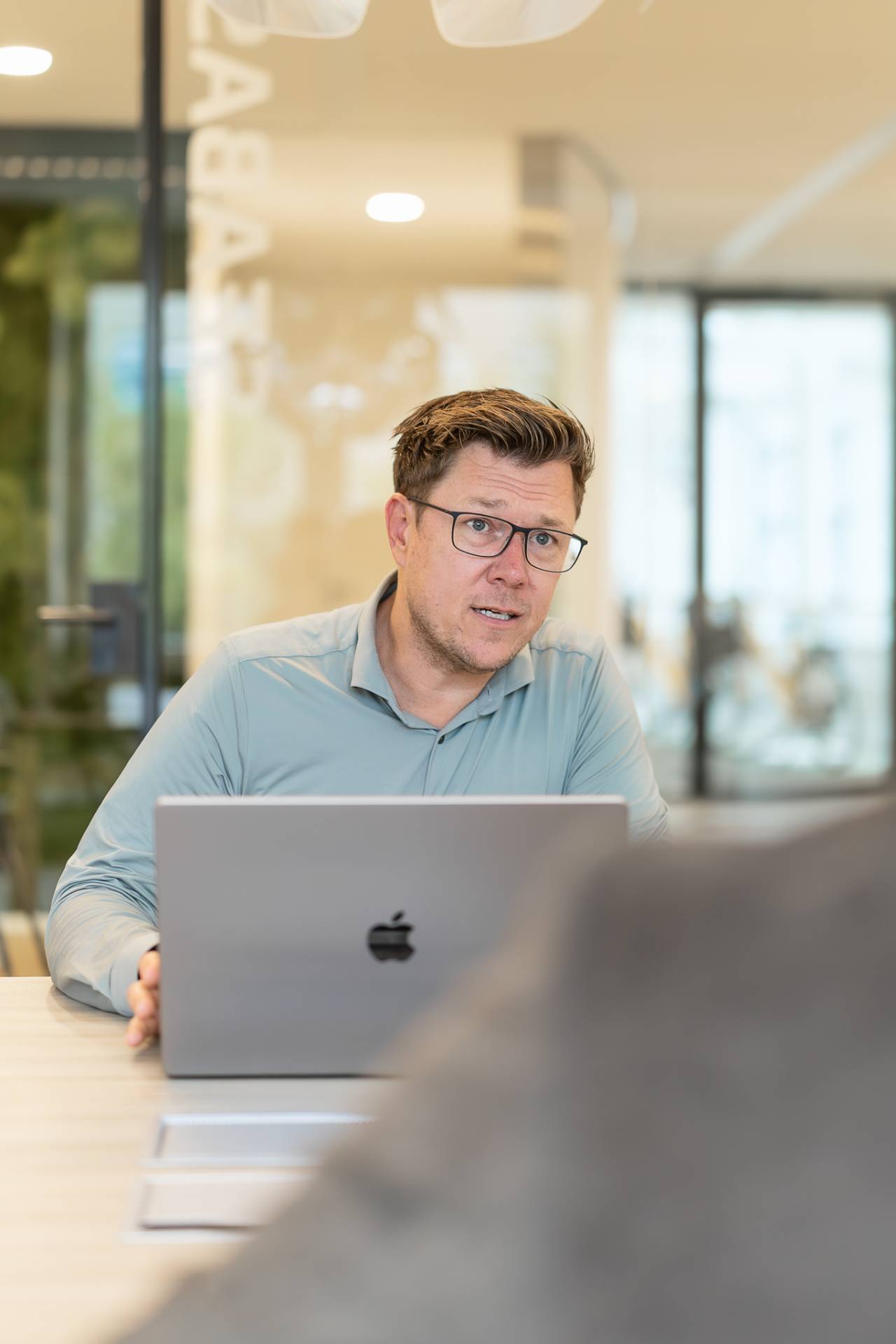 Man met blauw overhemd achter laptop.