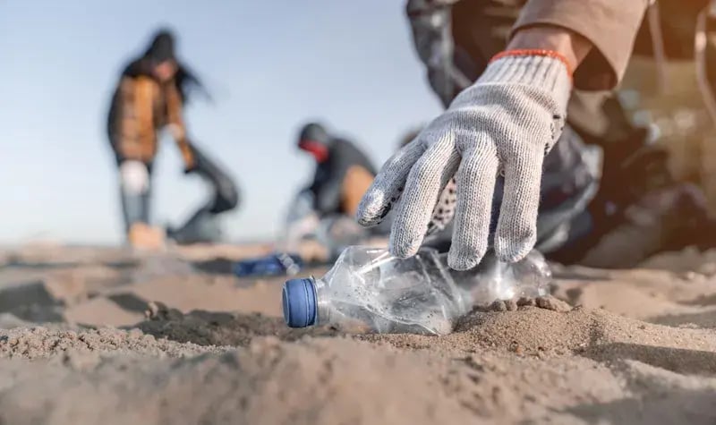 Plasic flesje op het strand dat op geruimd wordt. 
