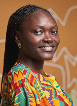 Black woman wearing a colourful blouse smiling into the camera.