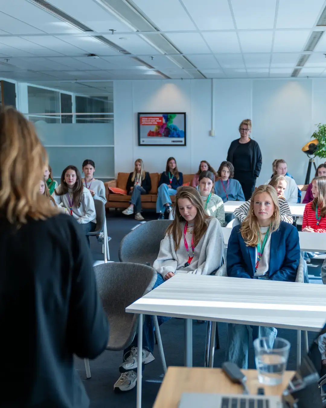 Groep jonge meiden luisterend naar een presentatie.