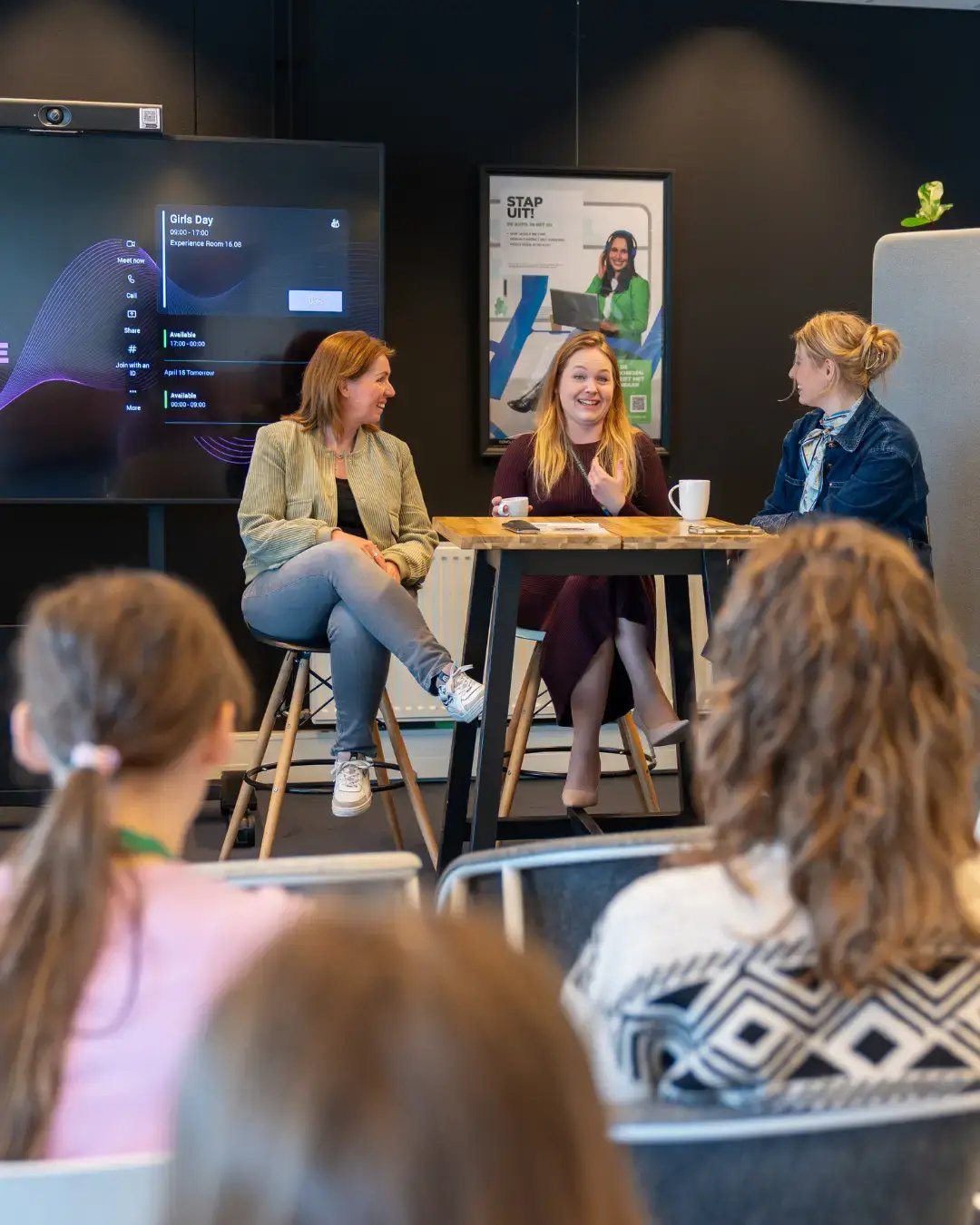 Drie vrouwen achter een tafel zittend op een kruk.