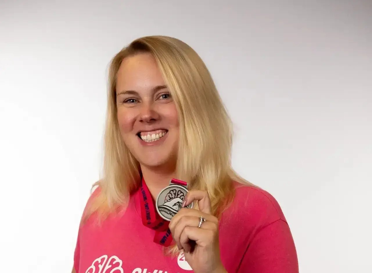 Woman proudly holding a medal.