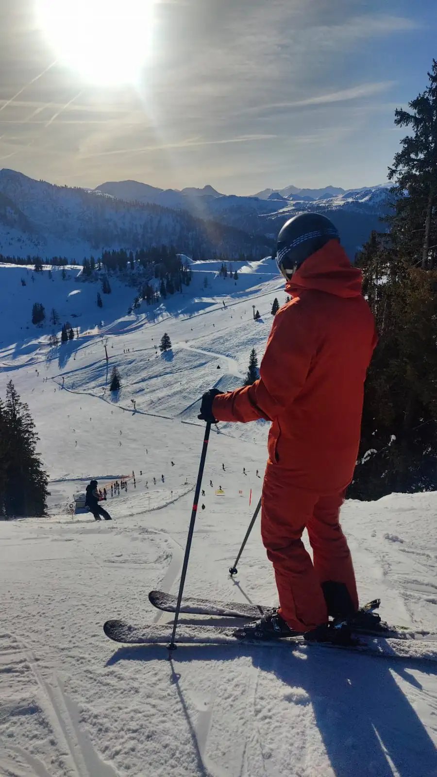 Skier in a red ski suit looking out over the slope.
