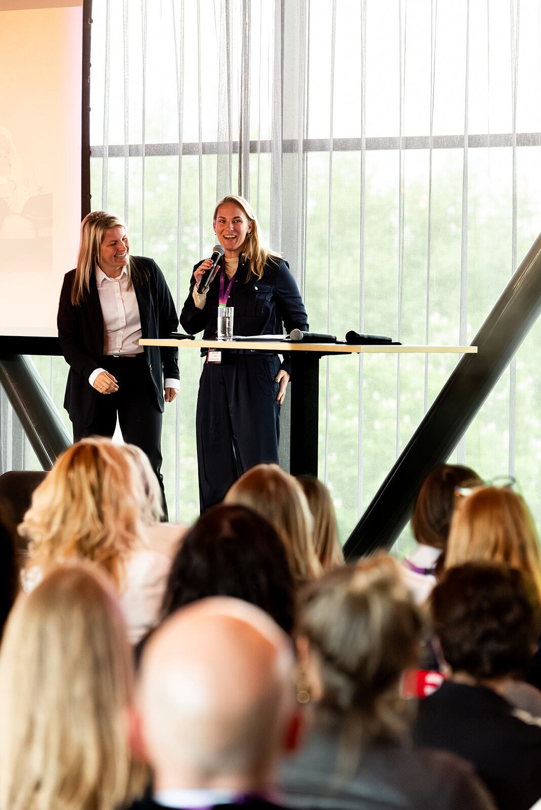 Twee vrouwen op het podium die presenteren.