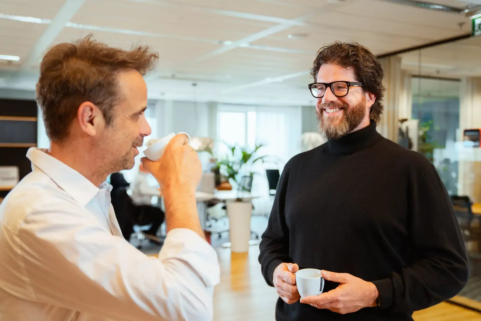 2 mannen met elkaar in gesprek met koffie.