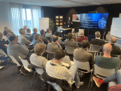 Groep collega's kijkt naar scherm tijdens een presentatie.