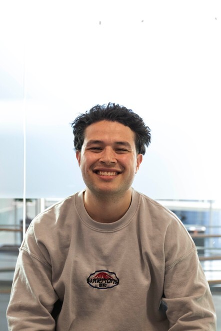 Getinte jongen met kort haar lacht in camera.