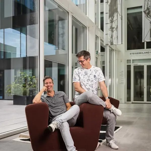 Paul en Emiel lachend op en een donker rode stoel