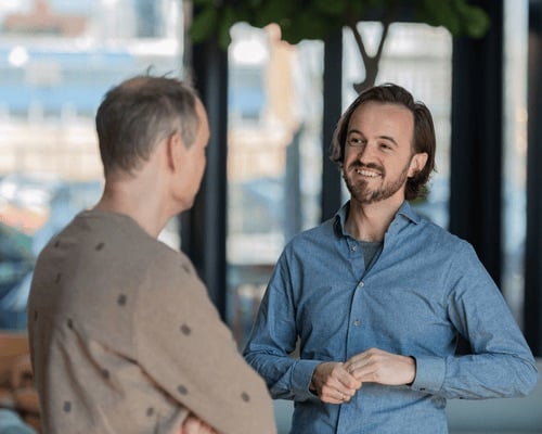 Twee mannen staan in een open ruimte en lachen met elkaar.