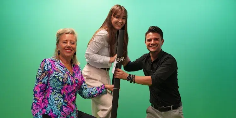 Group photo with a woman on the left, a woman on a ladder in the middle, and a man on the right holding the ladder.