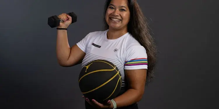 Self-portrait of Djill holding a weight and a basketball in her hand.