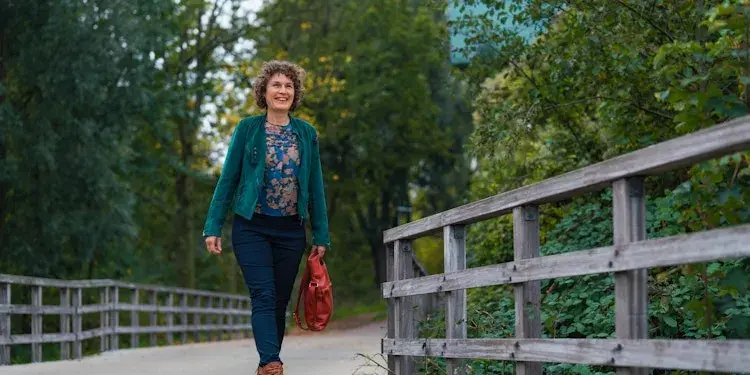 Woman walking across a bridge in a park.