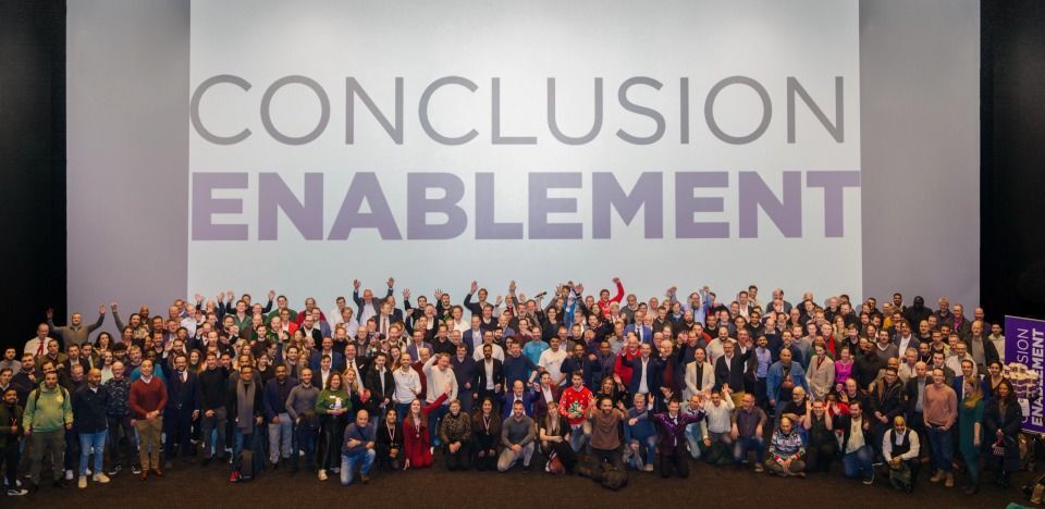 A group of people pose for a photo with the 'CONCLUSION ENABLEMENT' logo in the background