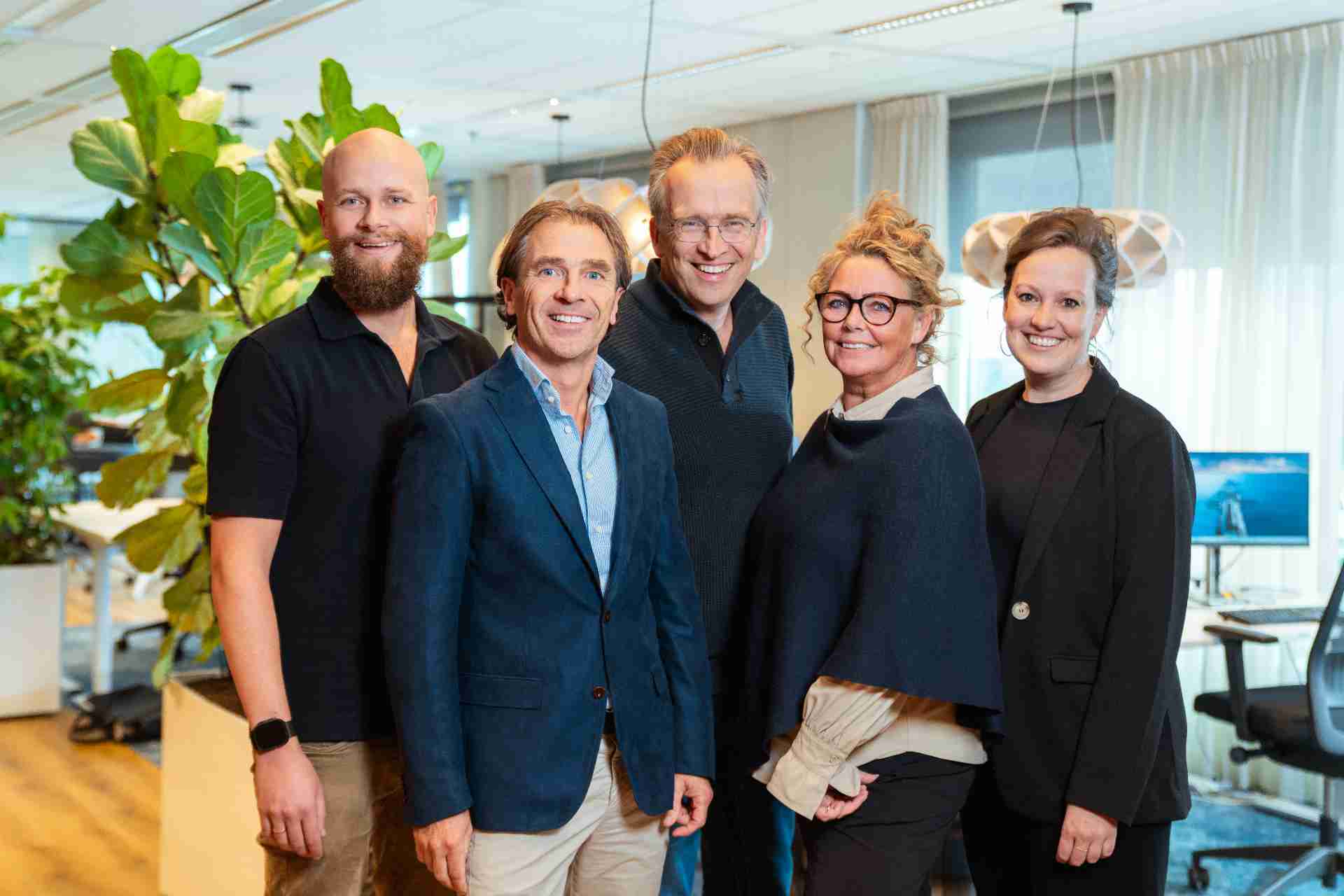 5 mensen die in camera kijken.