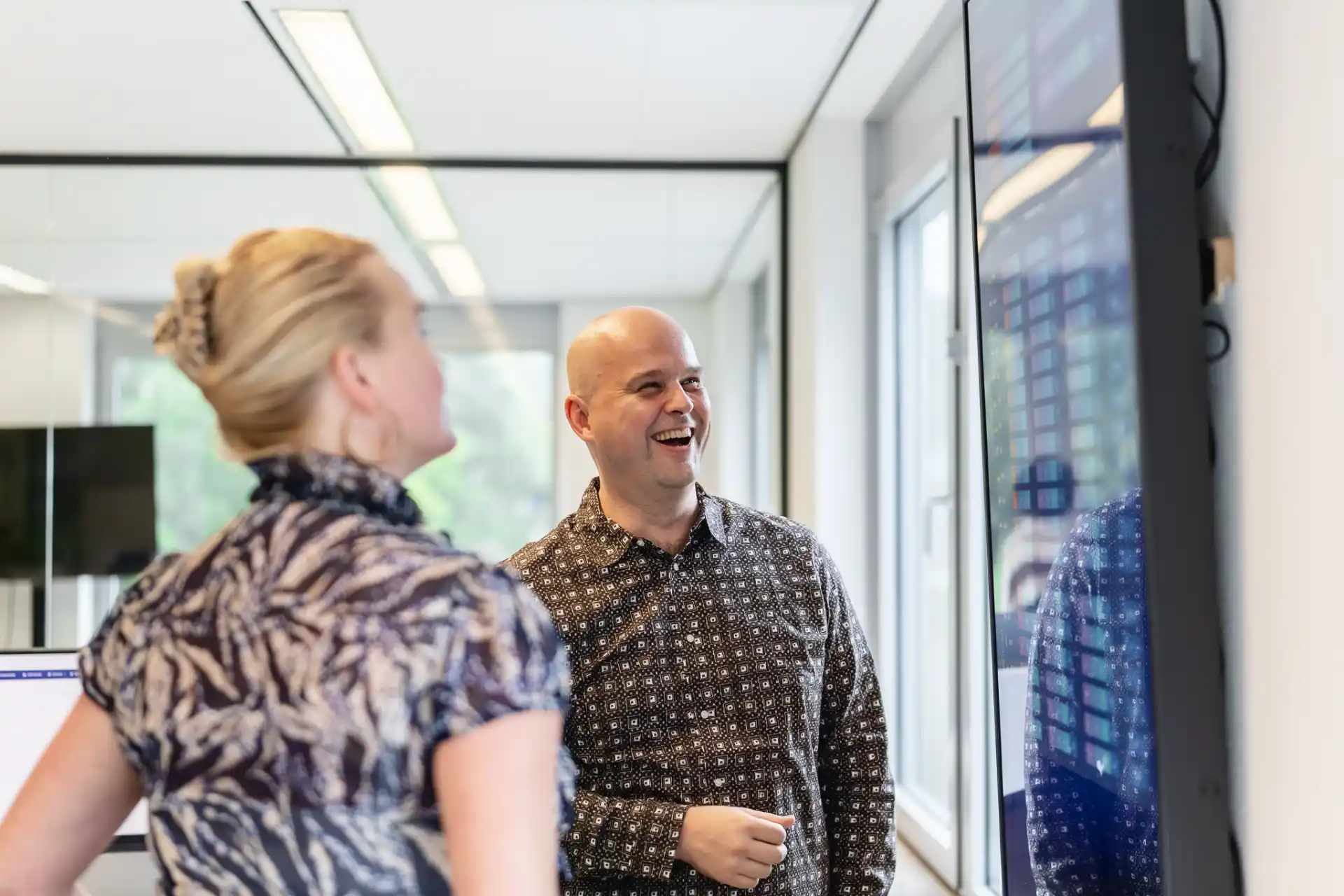 Man en vrouw in gesprek voor een scherm.